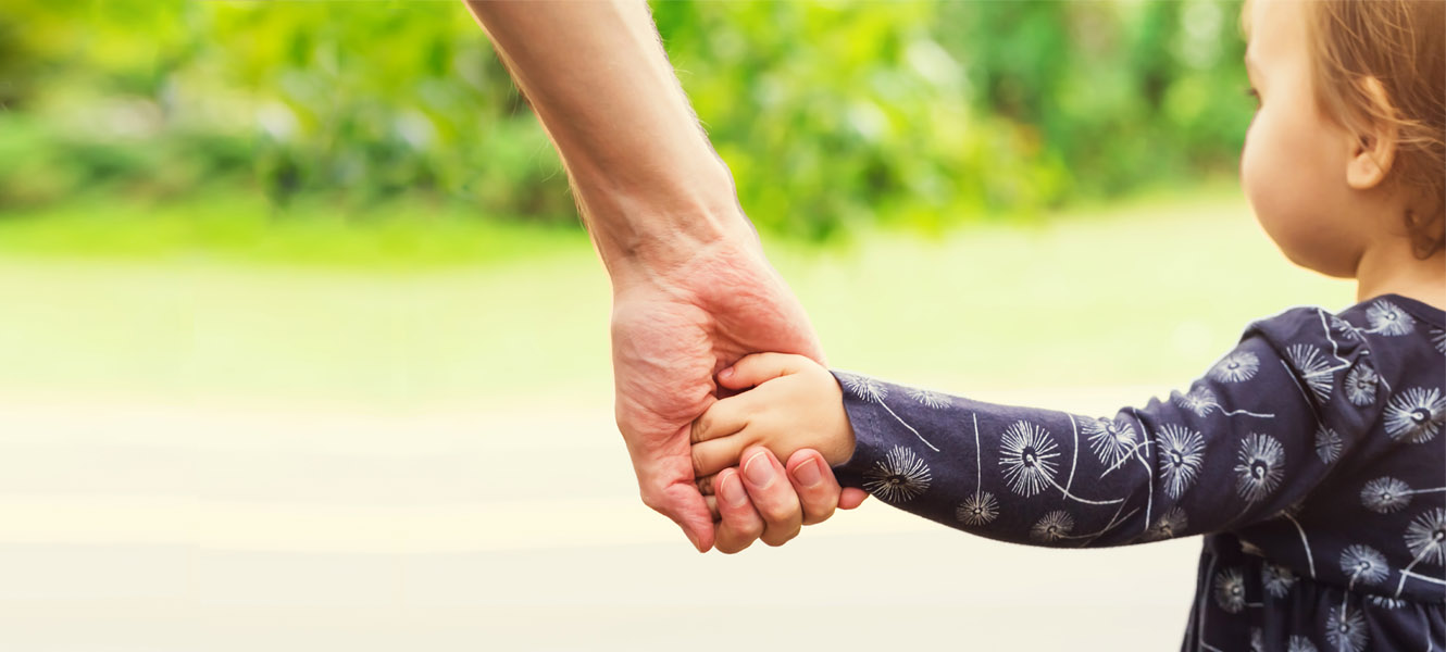 An adult holding a little girls hand